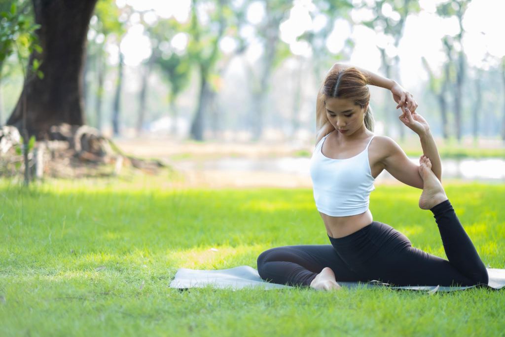 Portrait of young woman practicing yoga in garden.female happiness. blurred background.Healthy lifestyle and relaxation concept.Young Asian Girl doing yoga in the park.